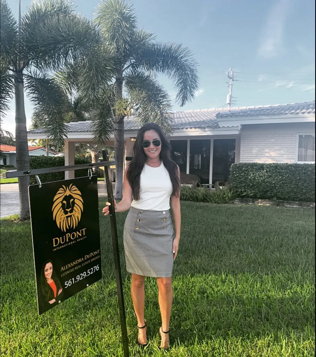 Alexandra DuPont beside a DuPont International Realty sign in front of a South Florida home